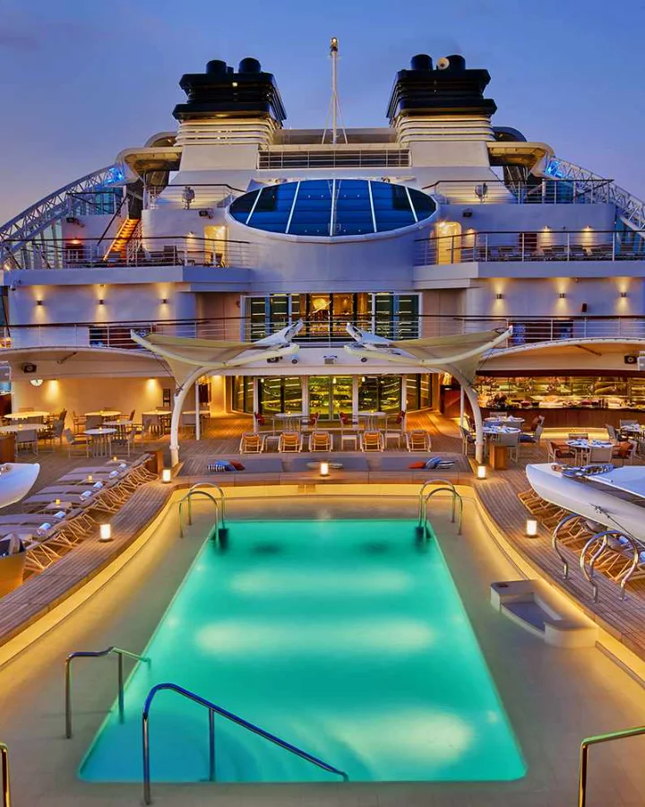 Illuminated pool deck of a cruise ship at dusk