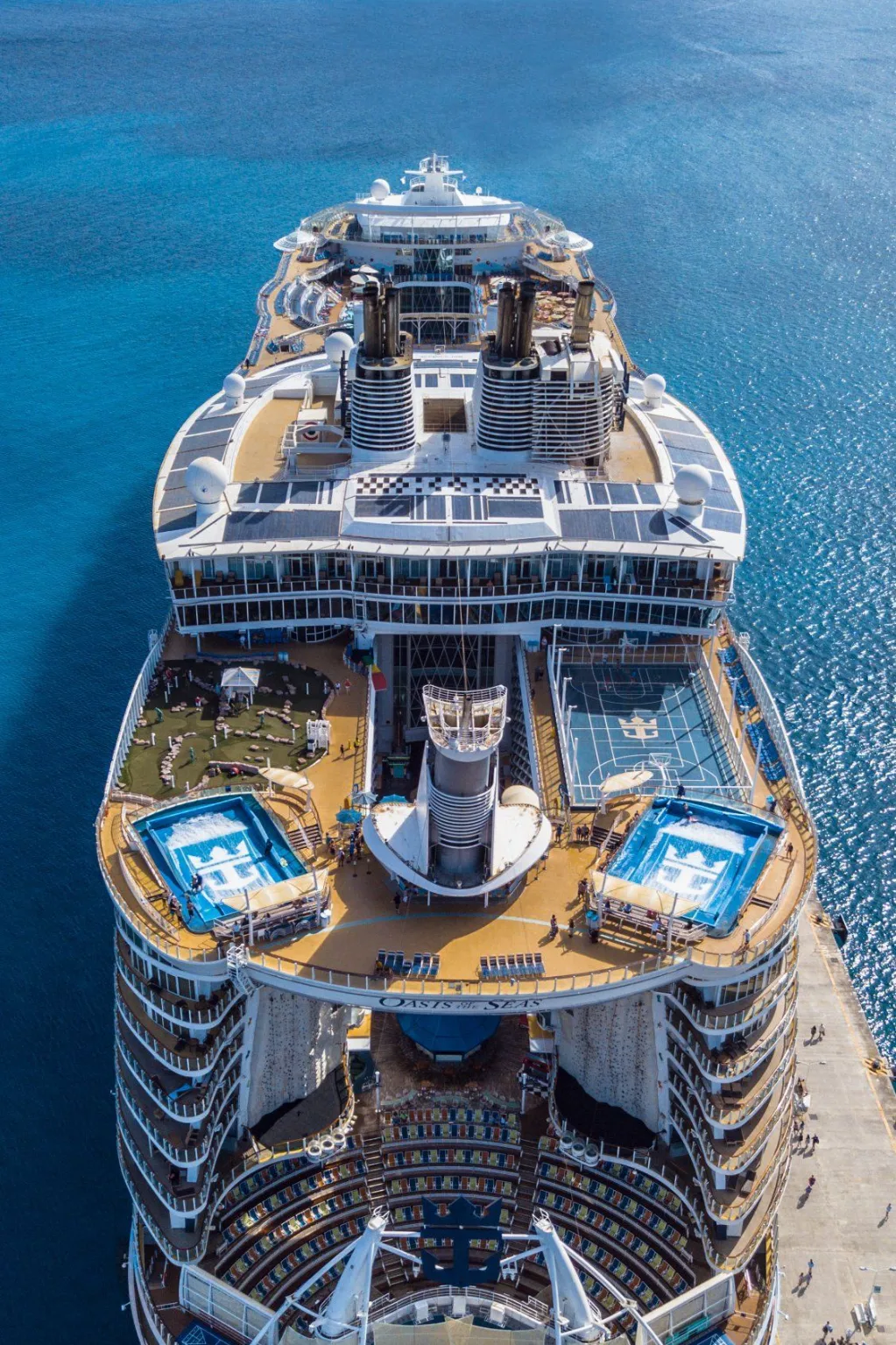 Aerial view of a large cruise ship with pools and sports courts