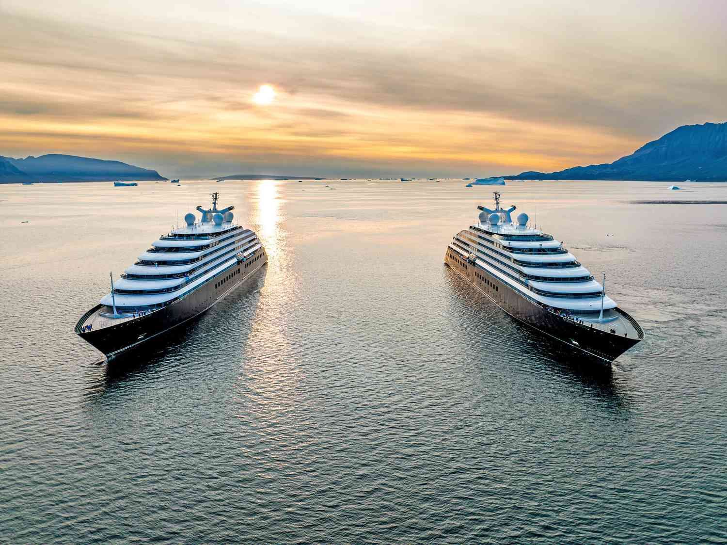 Two cruise ships at anchor in a calm bay at sunset