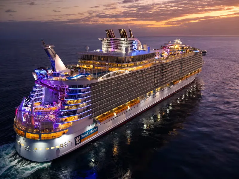 Cruise ship lit up at dusk on calm water